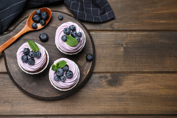 Sweet cupcakes with fresh blueberries on wooden table, flat lay. Space for text - Powered by Adobe
