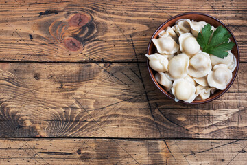 Traditional pelmeni, ravioli, dumplings filled with meat on plate, russian kitchen. Wooden rustic background, copy space.