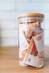 Russian banknotes of 5000 rubles packed in a glass jar on a kitchen. Business, finance concept. Saving money.