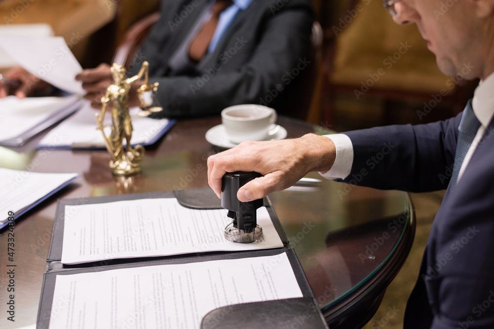 Aufkleber hand of director of large business company putting stamp on document after reading and signing it