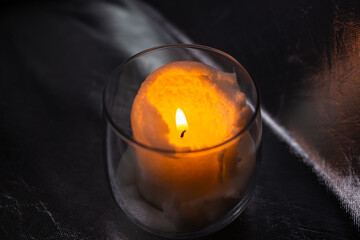 White candle burns in a bowl on a silver background
