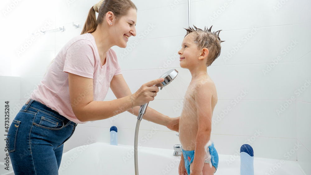 Wall mural Little boy smiling at mother while she is washing him in bath. Concept of hygine, children development and fun at home