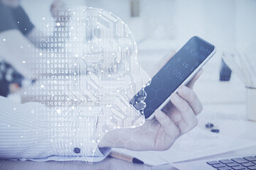 Double exposure of man's hand holding and using a digital device and brain hologram drawing. Data concept.