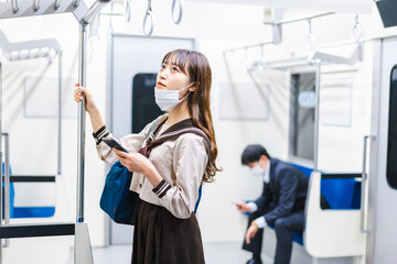 鼻だしマスクをして電車にのる女子高生