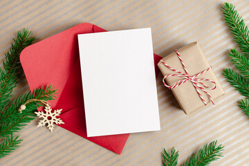 Christmas greeting card mockup with red envelope, gift box and fir tree branches