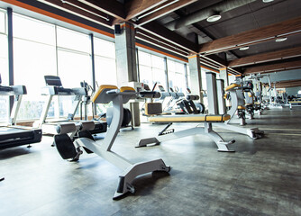 Modern gym interior with fitness equipment and exercise machines. Sports hall with large windows