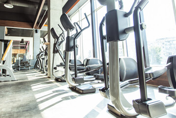 Modern gym interior with fitness equipment and exercise machines. Sports hall with large windows