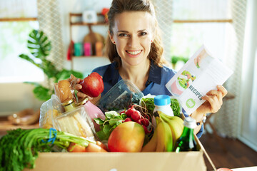 smiling modern woman with food box in kitchen