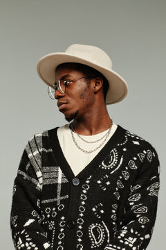 Vertical side view portrait of African American man in style wearing hat against grey background