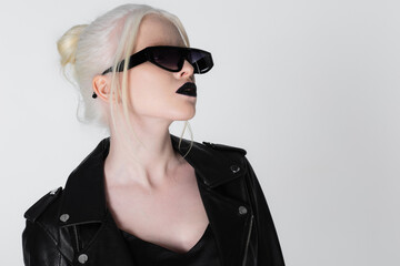 Fashionable albino woman in black sunglasses and leather jacket isolated on white.