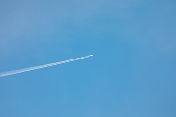 Trail of white smoke from the airplane in the blue sky