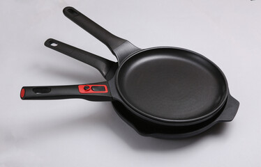 Stack of frying pans on gray background