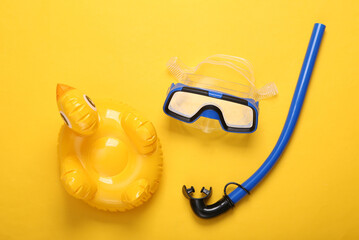 Diving mask and snorkel, inflatable duck on a yellow background. Top view