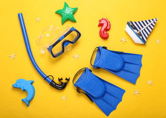Children's beach accessories. Diving set and sand toys on a yellow background. Top view © splitov27