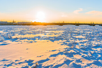 The embankment of Saint Petersburg in winter at sunset. The Neva River is covered with snow