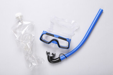 Polluted ocean. Diving set and plastic crumpled bottle on gray background