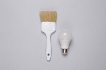 Paintbrush with lightbulb on gray background. Creative layout