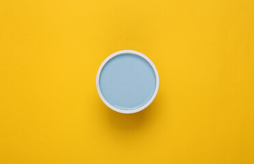 Can of turquoise paint on yellow background. Top view