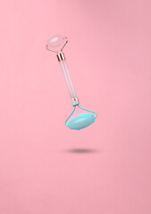Levitating massage roller with dripping turquoise paint on a pink background. Minimal creative...
