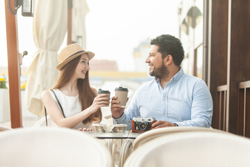 Fototapeta na wymiar Young international couple drinking coffee in outdoor cafe