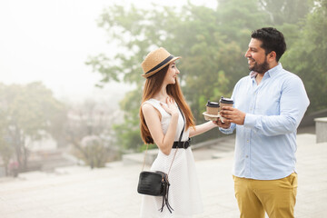 Young international couple drinking coffee on the go in the city