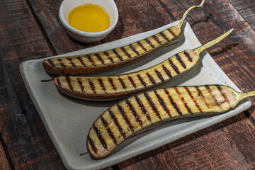 Grilled eggplants in plate on wood background.