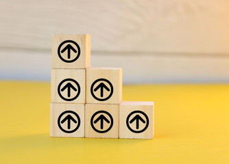The wooden blocks are lined with an up arrow icon. The process of creating a successful business idea