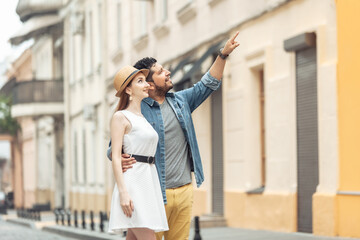 Young loving international couple of tourists contemplate architecture on a European street