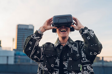 Happy man enjoying wearing virtual reality headset in city