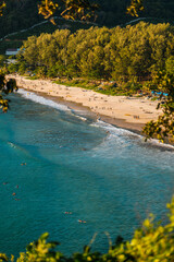 Aerial view of white sand tropical beach sunset light, golden hour, people with surf. Vertical photo