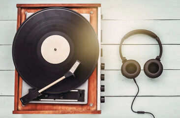 Retro vinyl player and stereo headphones on blue wooden background. Top view. Flat lay