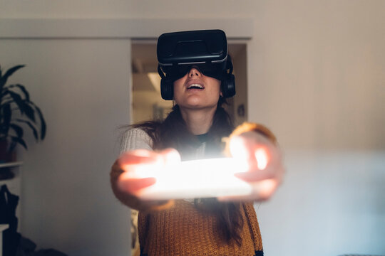 Woman holding LED light wearing virtual reality headset at home