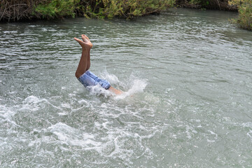 Man jumping with joy by a lake. Cliff Jumping into the river water, Summer Fun Lifestyle. Healthy, fit and muscular man jumping for joy on a beach
