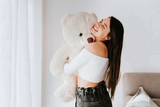 Naklejki Young woman hugging teddy bear at home