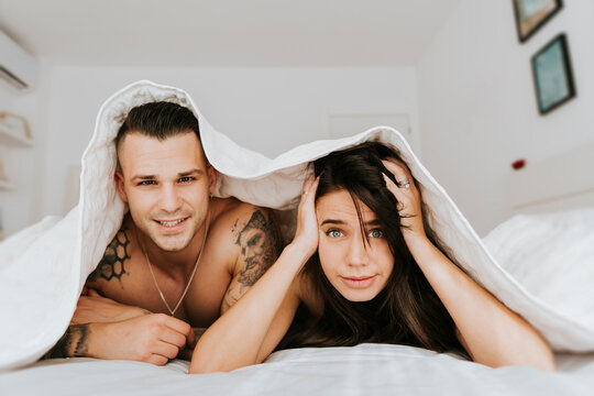 Young Couple Lying On Bed Under Duvet