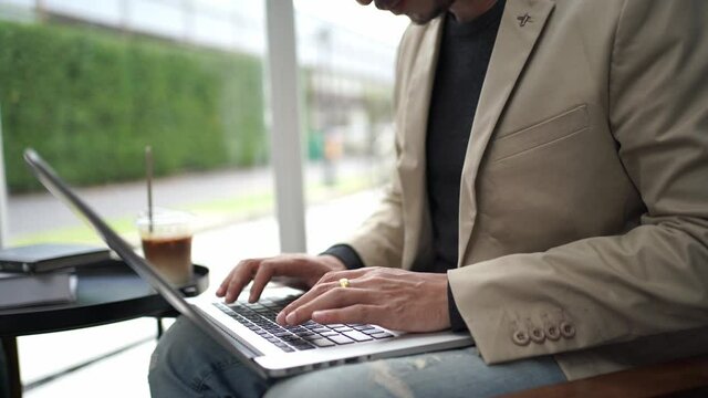 Close up hand young businessman using laptop typing working in cafe