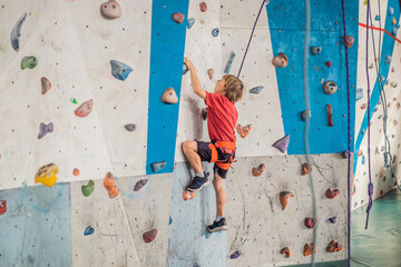 Boy at the climbing wall without a helmet, danger at the climbing wall - obrazy, fototapety, plakaty