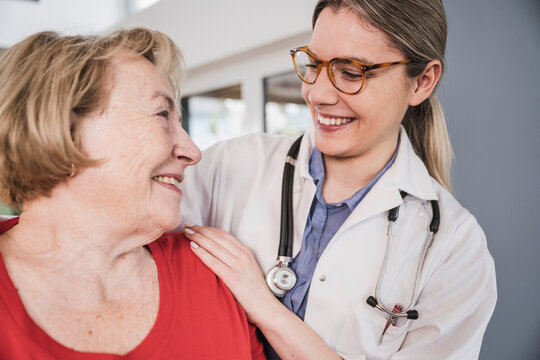 Smiling doctor with hand on senior patient's shoulder at home
