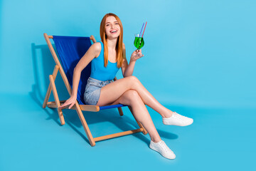 Photo portrait red haired woman happy drinking cocktail at party sitting in chair isolated pastel blue color background