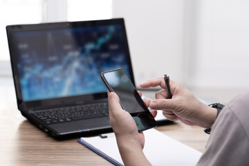 Business man use smartphone Check stocks and investments online and use laptop working business work in office