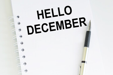 Hello, December entry on a white notepad on a table next to a pen