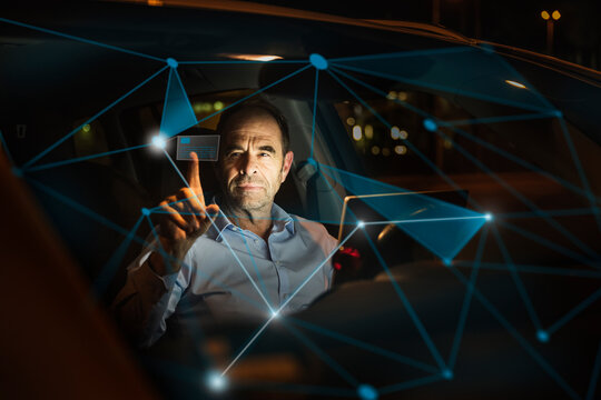 Businessman working on futuristic graph in car at night