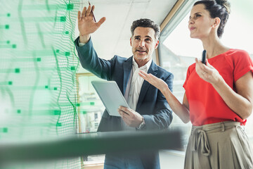Businessman discussing with colleague over futuristic business strategy at office