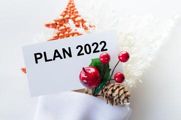 card with text plan 2022 next to Christmas decorations on white background