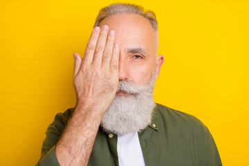 Photo portrait of senior man serious shut half face with hand isolated vibrant yellow color...