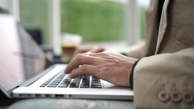 Close up hand young businessman using laptop typing working in cafe