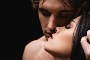 close up of young passionate couple with closed eyes isolated on black.