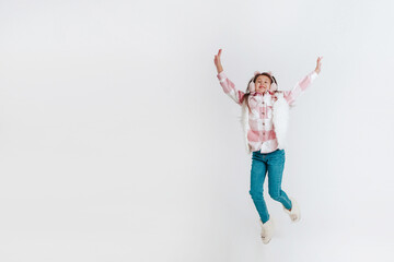 Happy little girl in warm clothes jumping on a white background. Space for text. 