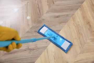Janitor cleaning parquet floor with mop, closeup. Difference before and after cleaning
