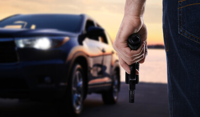 Man with gun near luxury car outdoors, closeup